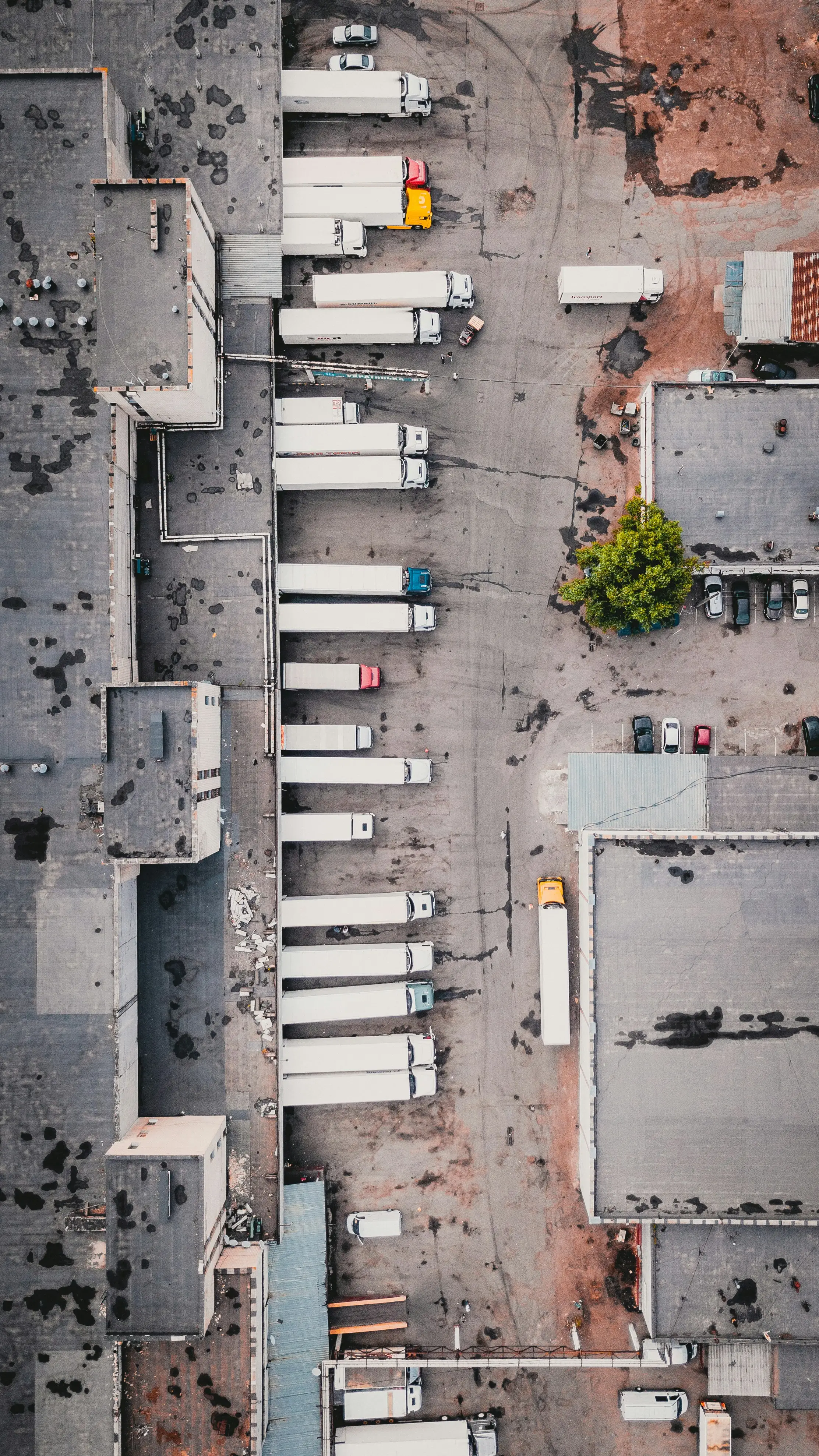 A parking lot with trucks beside an industrial building.